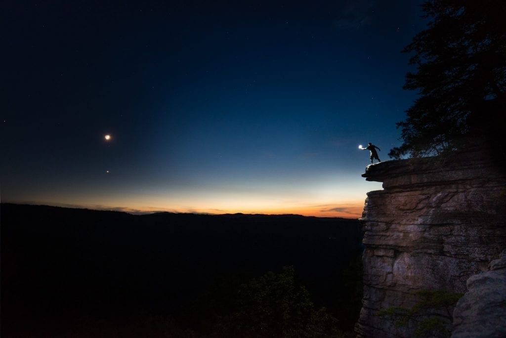 Leaning over the Endless Wall, a shadowy figure pretends of offer a star to the void of the New River Gorge.