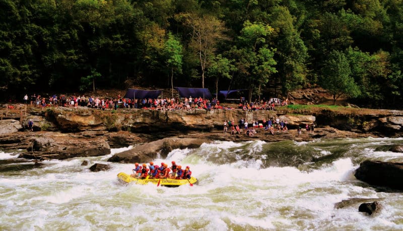 Rafters outfitted with River Expeditions watch raft-load plow through Sweets Falls on the Gauley River.