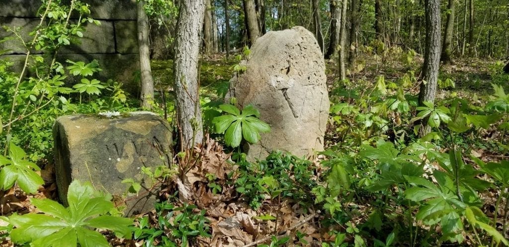 Salvaged state line markers stand alongside the grave.