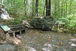 A bench and informational signage flank a honeycombed rock in Pocahontas County, West Virginia.