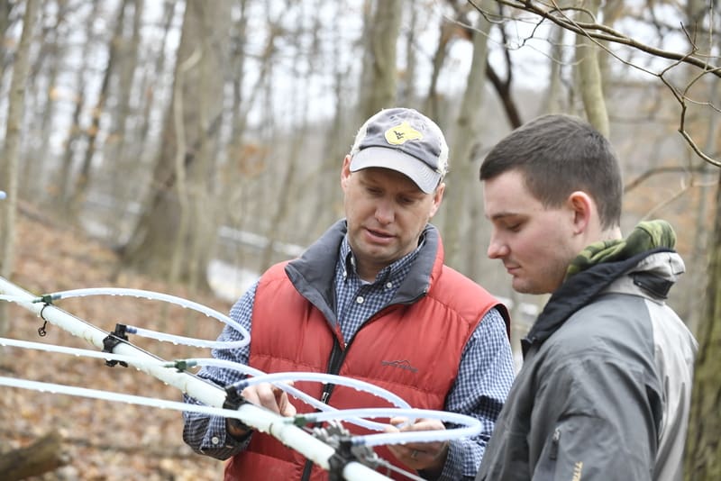 Professor Jame Schuler and students of the Davis College turn sap into syrup on West Road Run March 6th, 2018. Photo Brian Persinger Jamie Schuler (left), associate professor of silviculture, teaches a WVU student about maple syrup production.