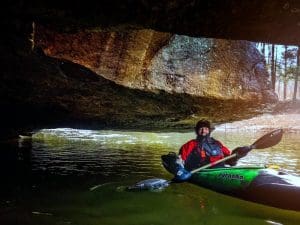 A kayaker paddles into a cave along Paint Creek.