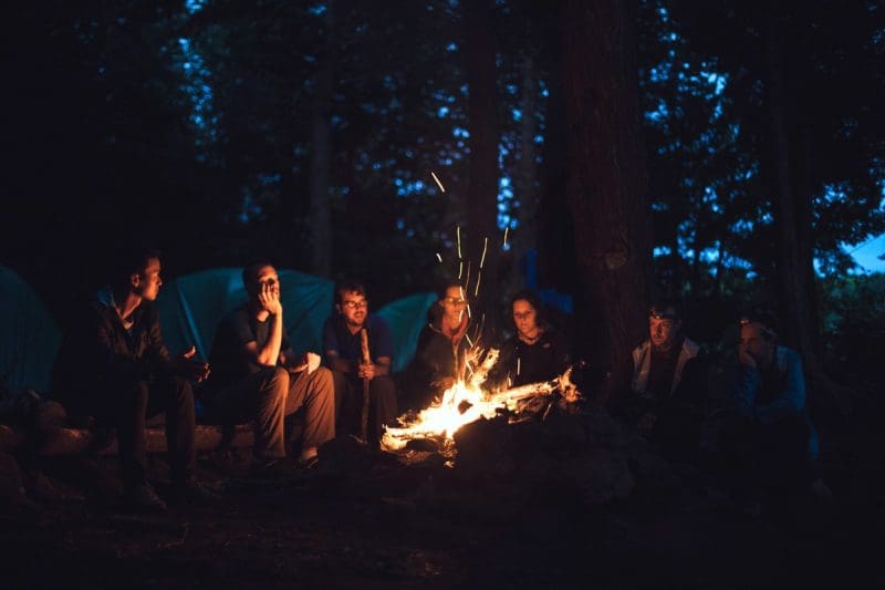 Campers gather around a fire in a West Virginia forest.