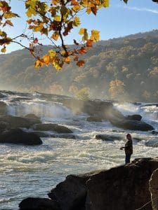 An angler casts into the New River below thundering Sandstone Falls. 